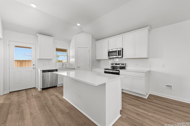 kitchen featuring white cabinetry, a center island, stainless steel appliances, backsplash, and lofted ceiling