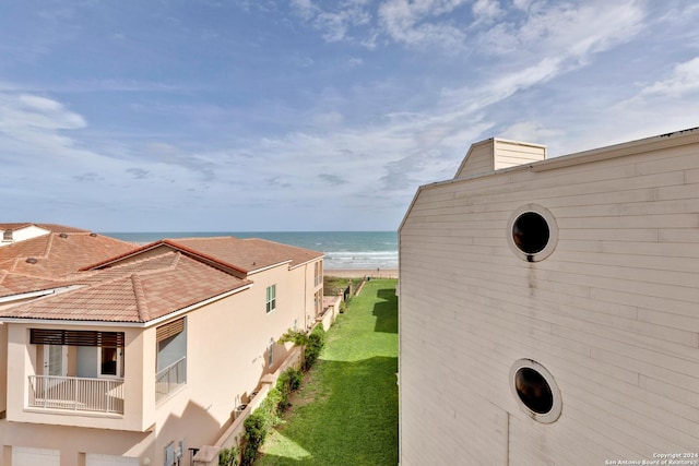 view of home's exterior featuring a view of the beach, a water view, and a lawn