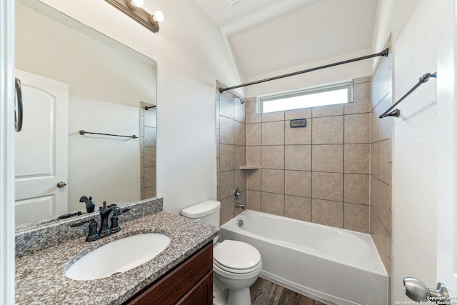 full bathroom with hardwood / wood-style floors, vaulted ceiling, toilet, vanity, and tiled shower / bath