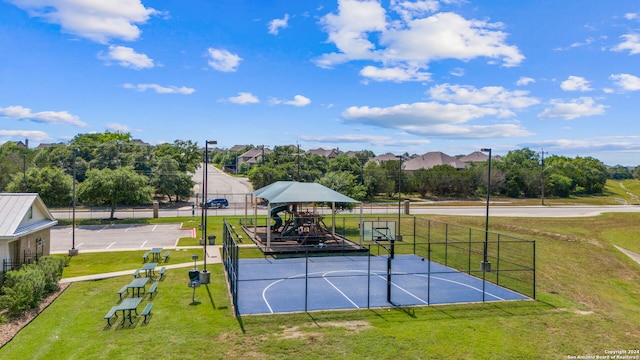 view of tennis court with a playground, basketball hoop, and a lawn