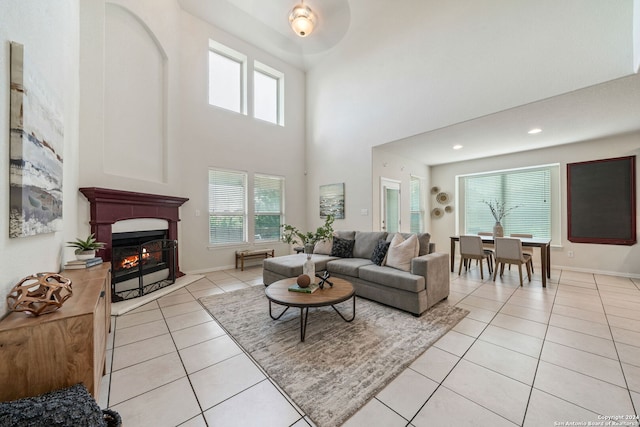 tiled living room with ceiling fan and a towering ceiling