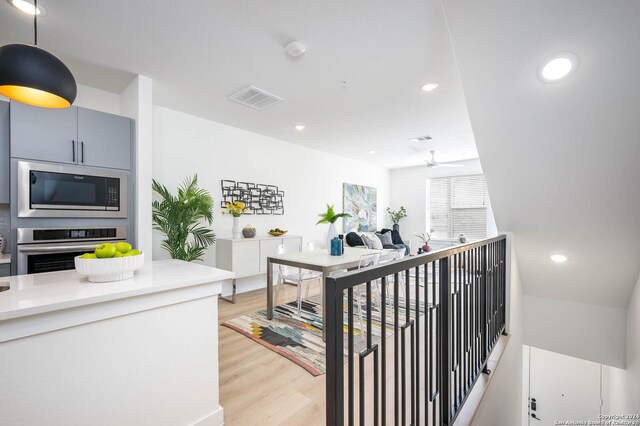 interior space featuring appliances with stainless steel finishes, light wood-type flooring, decorative light fixtures, and ceiling fan