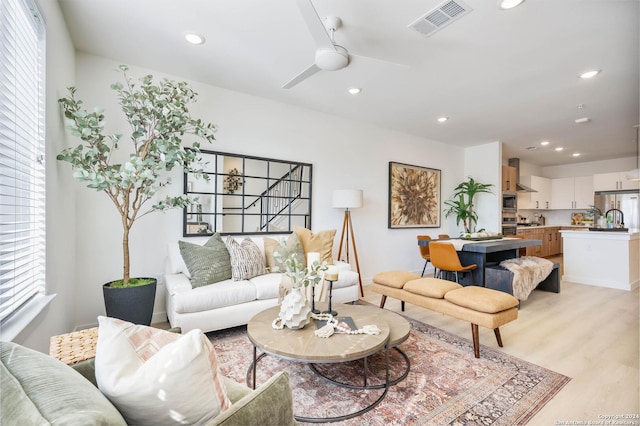 living room with light wood-type flooring, plenty of natural light, and ceiling fan