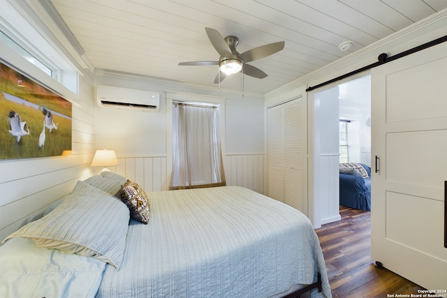 bedroom featuring a wall mounted AC, wood finished floors, a closet, wainscoting, and crown molding