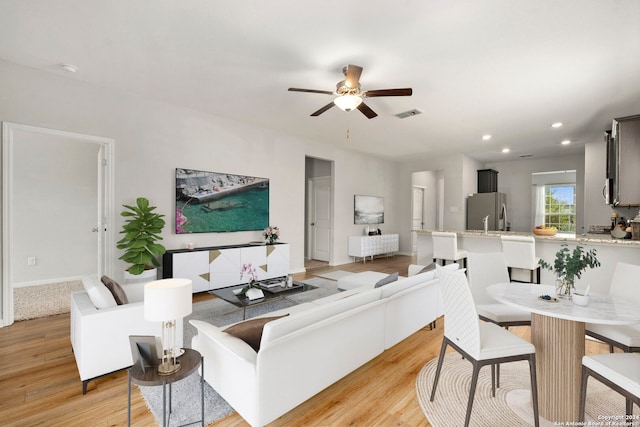 living room with ceiling fan and light hardwood / wood-style flooring