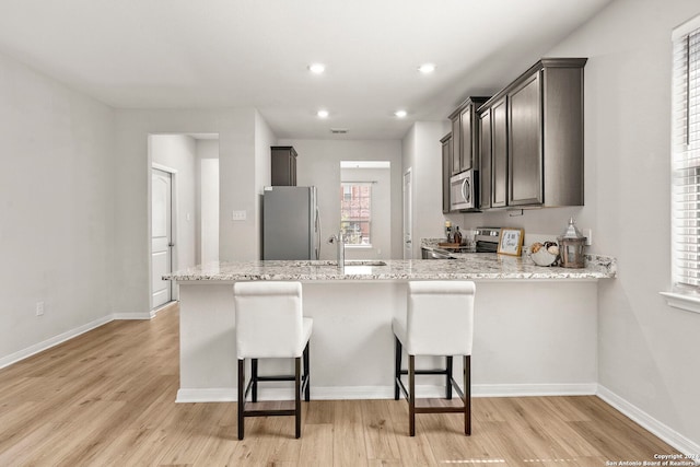 kitchen featuring a breakfast bar area, sink, stainless steel appliances, and light wood-type flooring