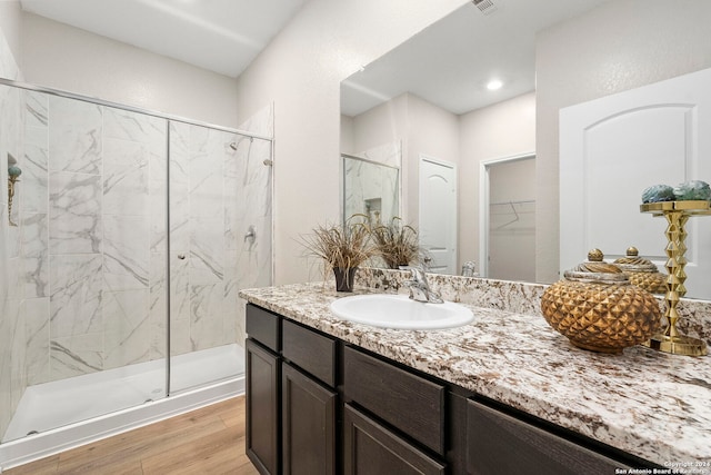 bathroom with hardwood / wood-style floors, vanity, and a shower with door