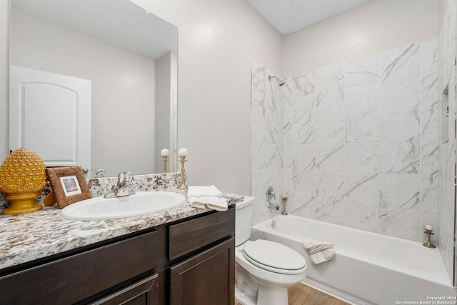 full bathroom featuring hardwood / wood-style floors, vanity, toilet, and tiled shower / bath