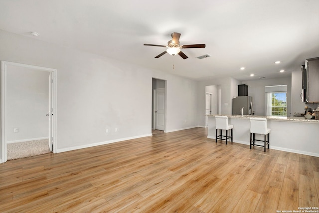 unfurnished living room with light hardwood / wood-style flooring and ceiling fan