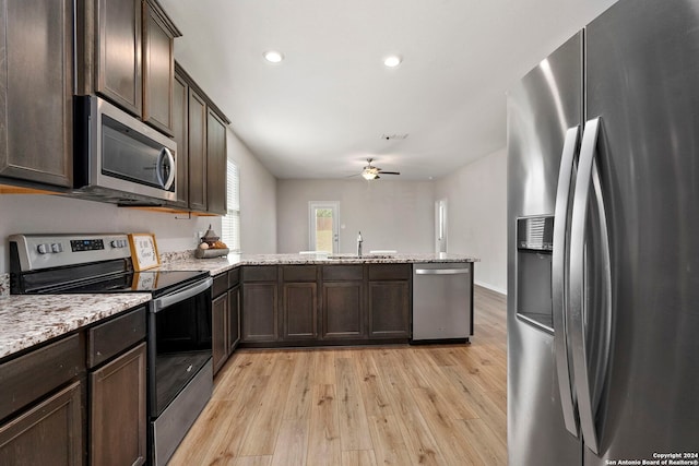 kitchen with kitchen peninsula, ceiling fan, stainless steel appliances, and light wood-type flooring