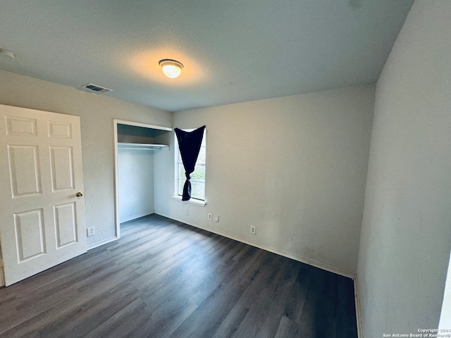 unfurnished bedroom featuring dark hardwood / wood-style flooring and a closet