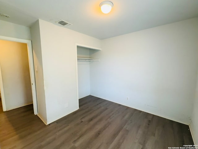 unfurnished bedroom featuring a closet and dark hardwood / wood-style flooring