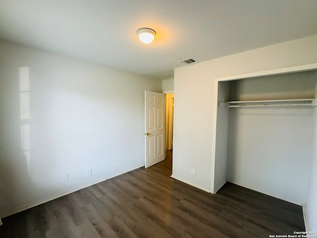 unfurnished bedroom featuring a closet and dark hardwood / wood-style flooring