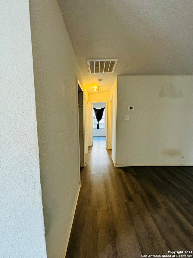 hallway with a textured ceiling and dark hardwood / wood-style floors