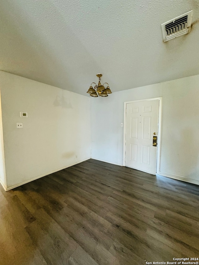 unfurnished room with dark hardwood / wood-style flooring, a textured ceiling, and a chandelier