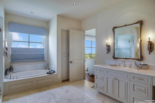 bathroom with a tub to relax in, a healthy amount of sunlight, and vanity