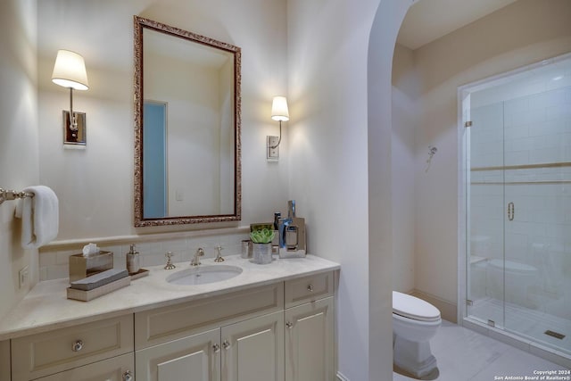 bathroom featuring vanity, a shower with shower door, and toilet