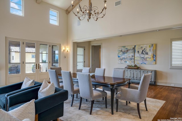 dining room with french doors, a chandelier, beam ceiling, hardwood / wood-style floors, and a high ceiling