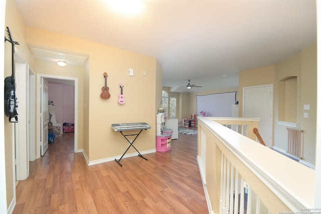 hall with light wood-type flooring, baseboards, and an upstairs landing