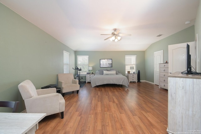 bedroom with visible vents, baseboards, lofted ceiling, light wood-style flooring, and ceiling fan