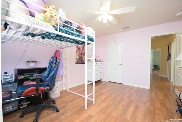 bedroom featuring a ceiling fan, wood finished floors, visible vents, and baseboards