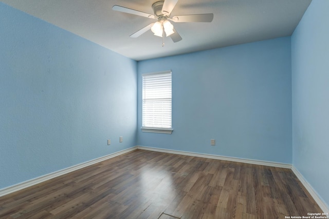 unfurnished room with dark wood-style floors, a ceiling fan, and baseboards