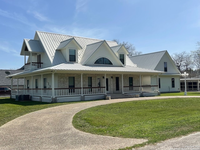 farmhouse-style home featuring a front lawn, covered porch, and central AC unit