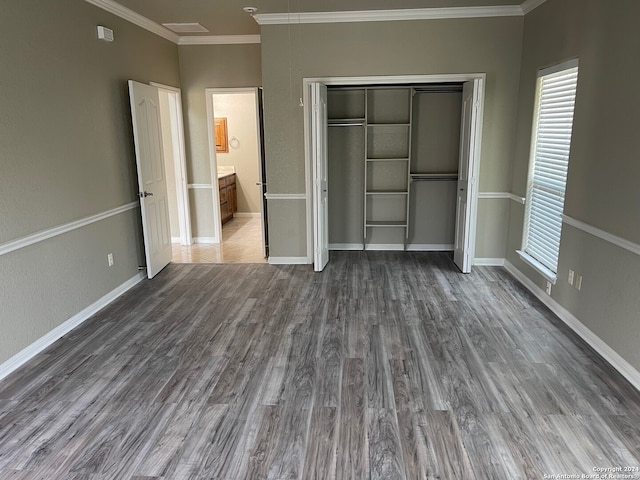 unfurnished bedroom featuring dark hardwood / wood-style floors, ensuite bath, a closet, and crown molding