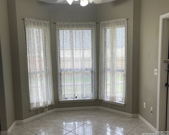 spare room featuring ceiling fan, a healthy amount of sunlight, and light tile patterned floors