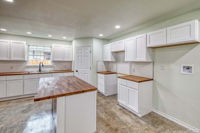 kitchen featuring wooden counters, sink, tasteful backsplash, and a kitchen island