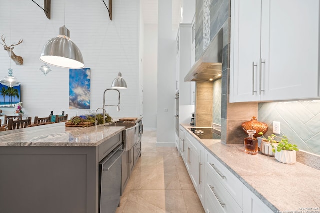 kitchen with white cabinets, light stone countertops, wall chimney exhaust hood, and a kitchen island with sink