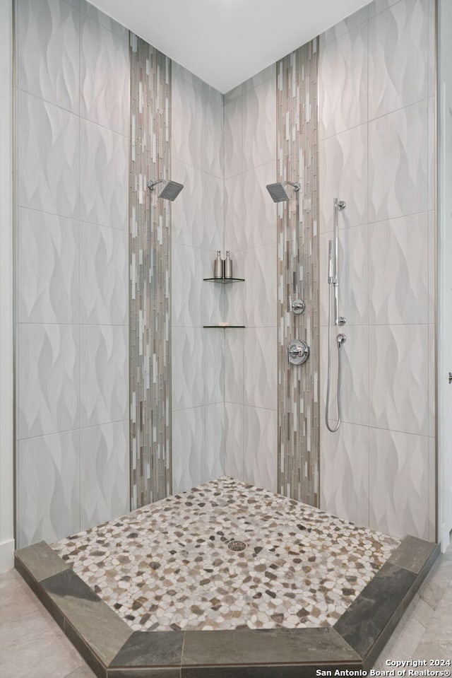 bathroom featuring tile patterned flooring, tiled shower, and tile walls