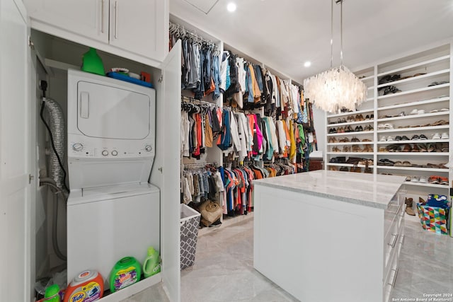 walk in closet featuring a notable chandelier and stacked washing maching and dryer