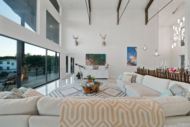 living room featuring beamed ceiling, a towering ceiling, and an inviting chandelier