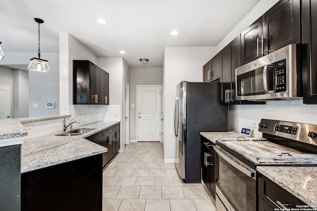 kitchen featuring tasteful backsplash, sink, hanging light fixtures, light stone counters, and stainless steel appliances