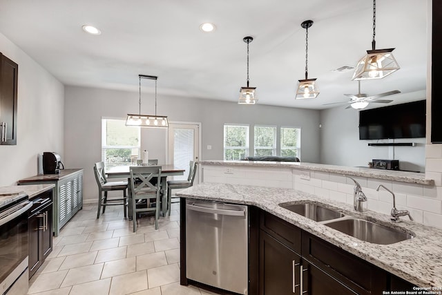 kitchen featuring pendant lighting, appliances with stainless steel finishes, sink, and light stone counters