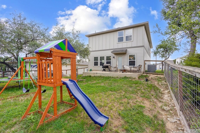 back of house featuring a trampoline, a lawn, and a playground