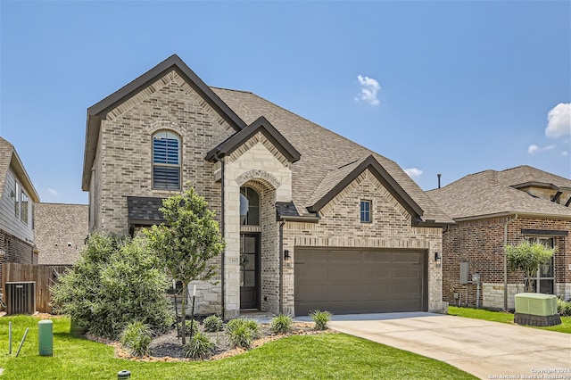 french country inspired facade with central AC unit, a front yard, and a garage