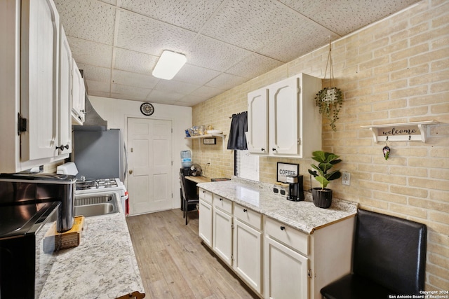 kitchen featuring white cabinetry, a paneled ceiling, stainless steel fridge, and light wood-type flooring