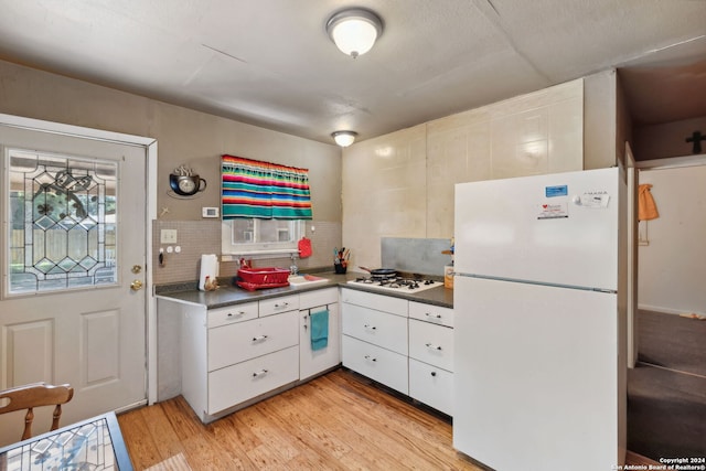 kitchen with tasteful backsplash, light wood-type flooring, white cabinets, and white appliances