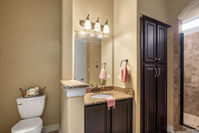 bathroom featuring a tile shower, vanity, and toilet