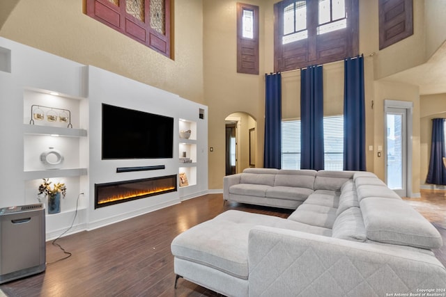 living room with built in features, plenty of natural light, and dark wood-type flooring