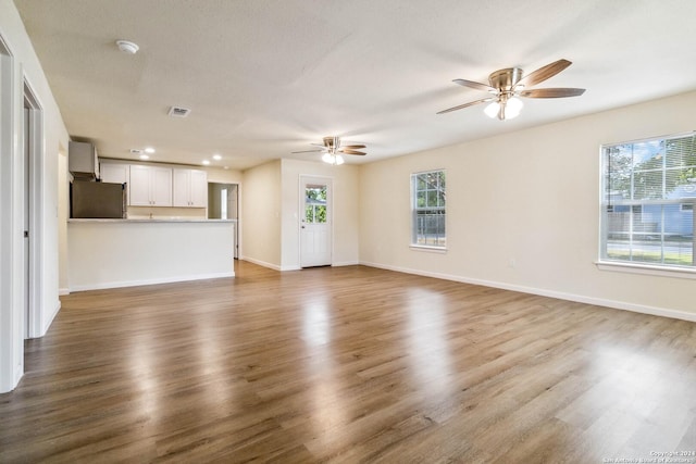 unfurnished living room with a textured ceiling, ceiling fan, and dark wood-type flooring