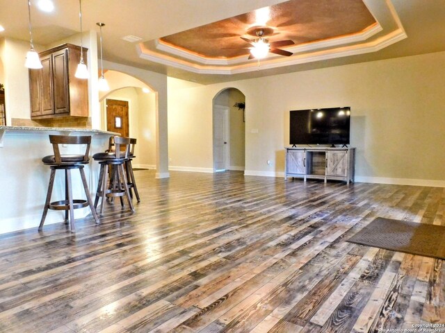 living room featuring hardwood / wood-style flooring, ceiling fan, and a raised ceiling