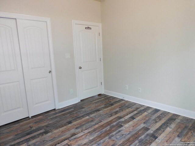 unfurnished bedroom with a closet and dark hardwood / wood-style flooring