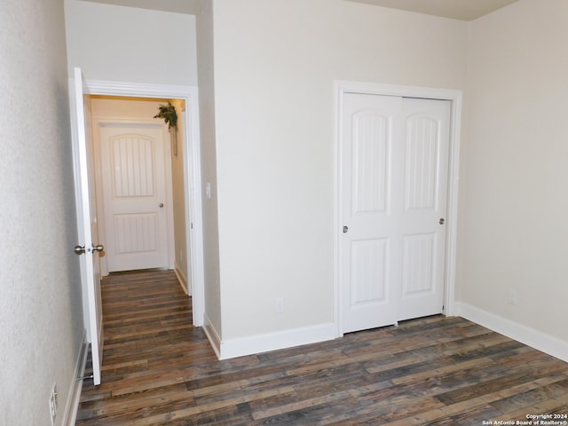 unfurnished bedroom with dark wood-type flooring and a closet