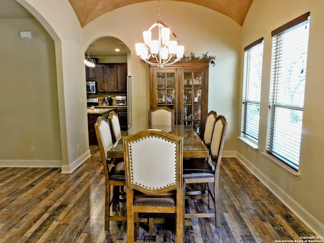 dining space with dark hardwood / wood-style floors, vaulted ceiling, and an inviting chandelier