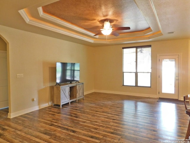 unfurnished living room featuring ceiling fan, a tray ceiling, crown molding, dark hardwood / wood-style flooring, and a textured ceiling