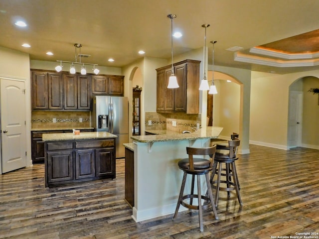 kitchen with backsplash, dark hardwood / wood-style flooring, pendant lighting, and kitchen peninsula