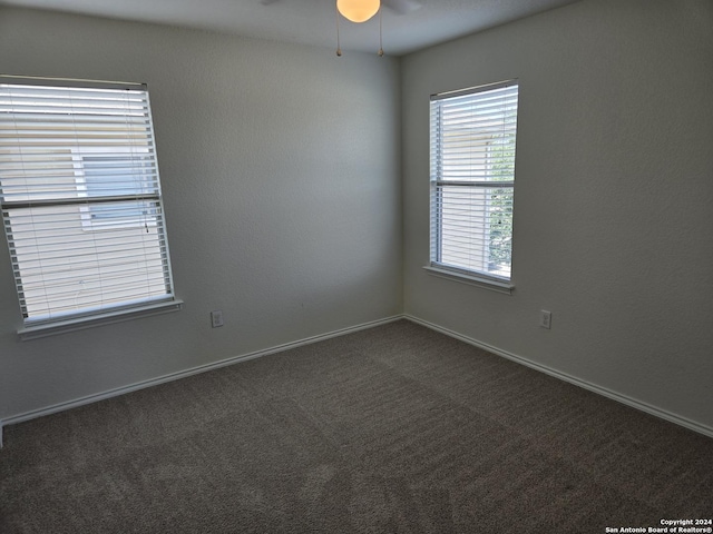 unfurnished room with ceiling fan and dark carpet